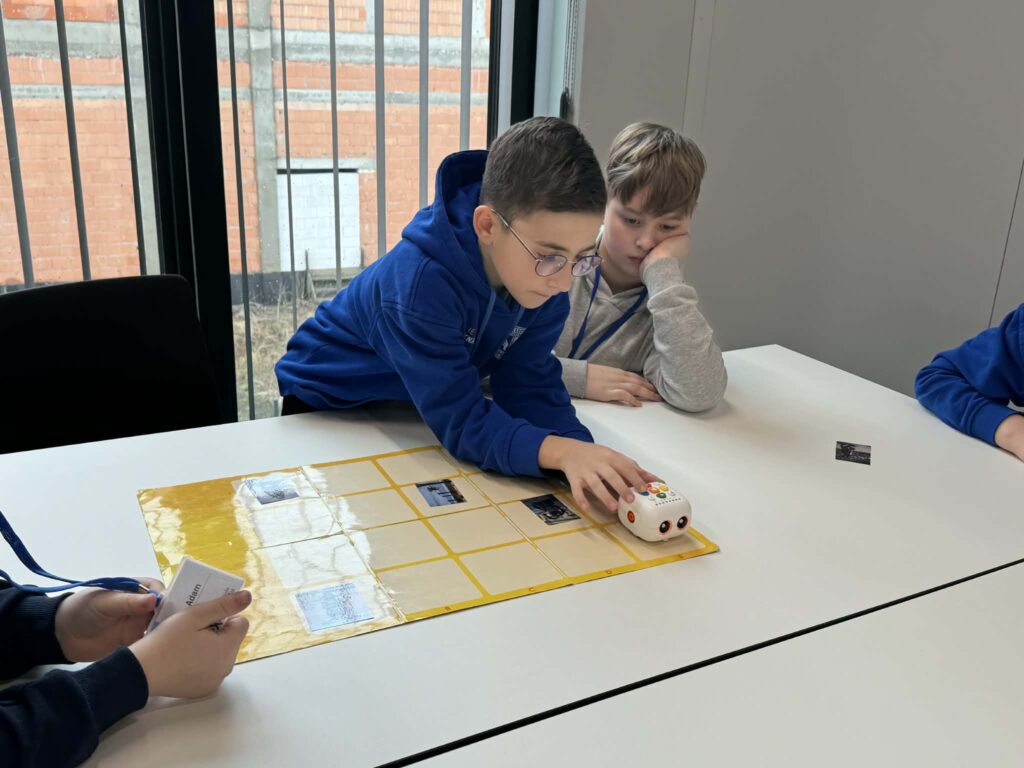 Dzieci siedzący przy stole i programujący robota. 