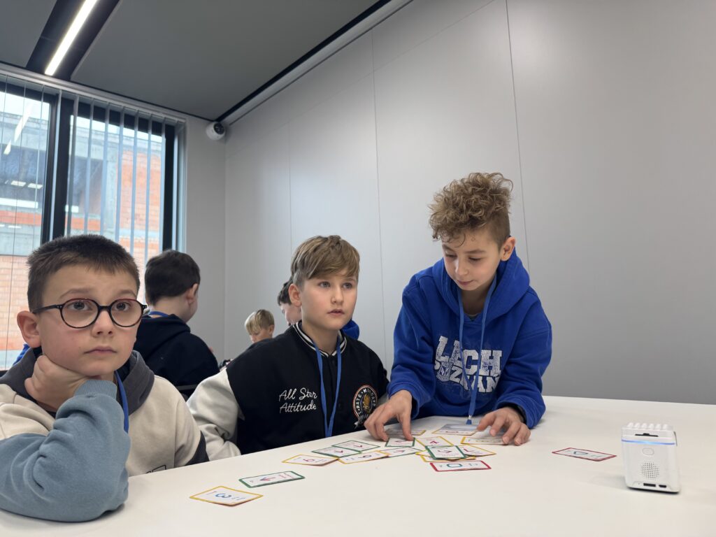 Chłopcy bawiący się robotem i kartami do niego. 