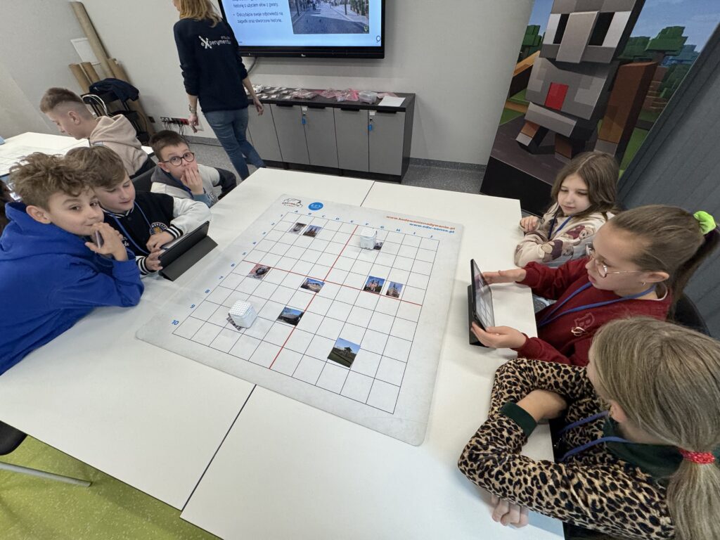 Dzieci siedzące razem przy jednym stole patrząc w tablety. 